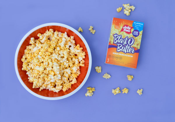 Blast O Butter microwave popcorn box sitting next to a bowl of Blast O Butter popcorn. You can't go wrong with Blast O Butter as a movie night treat!