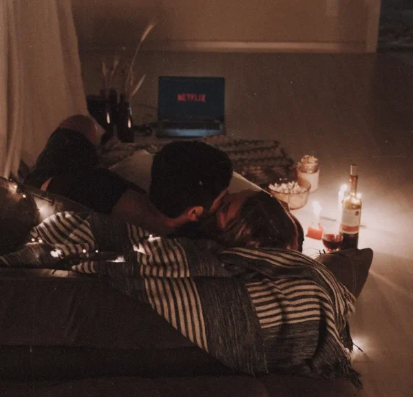 Get Romantic With 10 Movie Night Ideas At Home For Couples A couple curled up watching Netflix together.